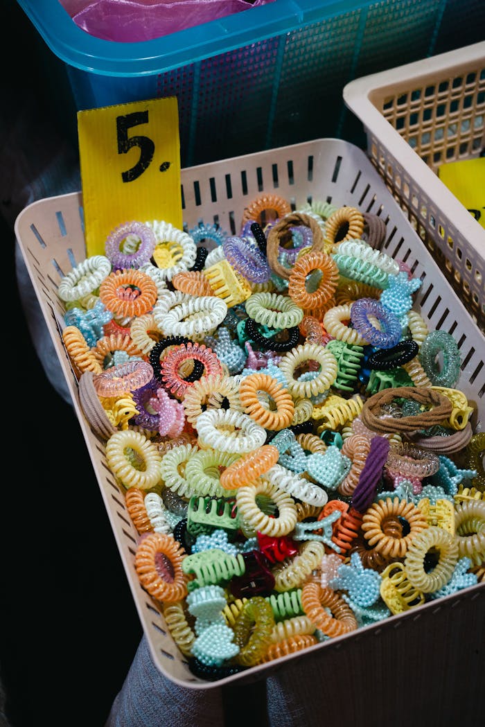 about-us A vibrant assortment of plastic hair ties displayed in a basket marked with a price.